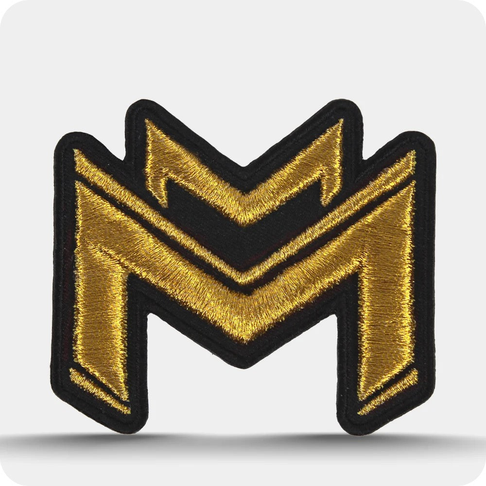 Woven navy clothing label beside a dimensional black and gold embroidered patch
