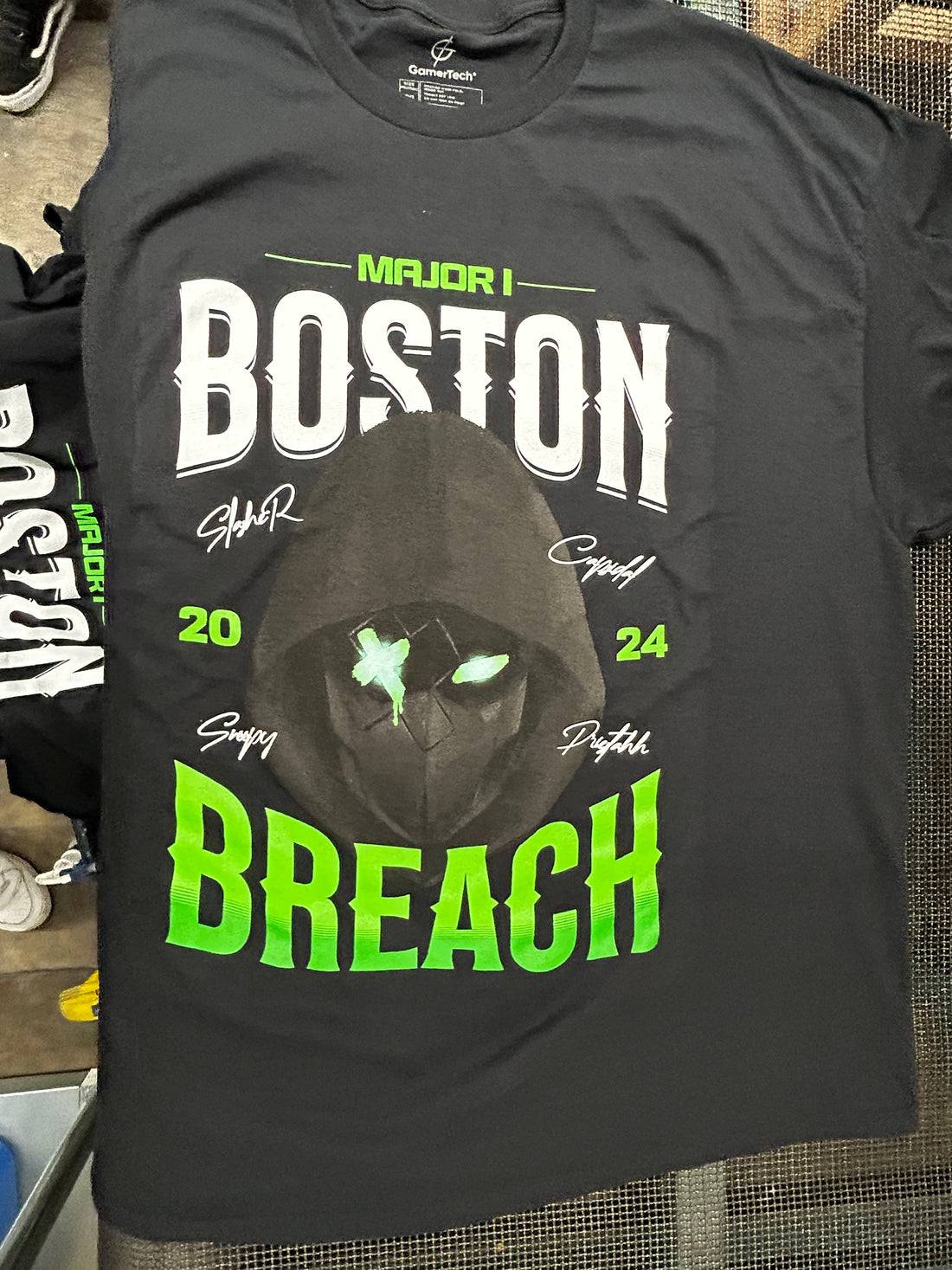 Black custom screen-printed shirt with a bold high-visibility graphic on the production floor